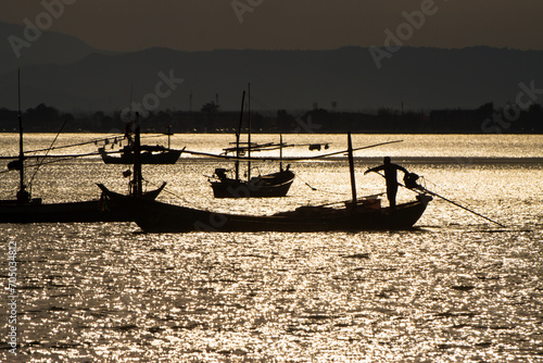 Silhouette image Landscape view evening silhouette Sunset on the ocean with fishing boats and mountain in the background