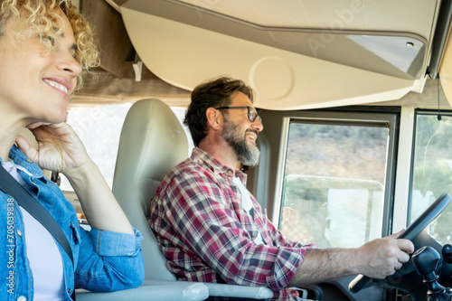 Man driving camper smiles while driving with his wife company. Concept of travel, vacation and life together