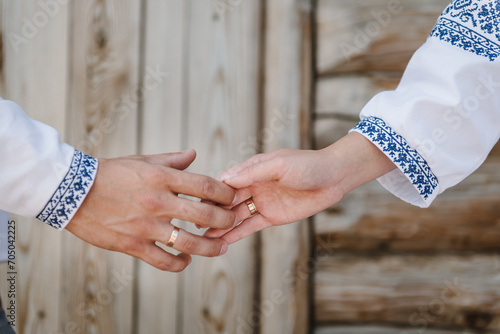 Hands are newlyweds with wedding rings. Rings and engagement. Bride and groom wearing embroidered dress and shirts hold hands together closeup. The Bride and groom holding hands.