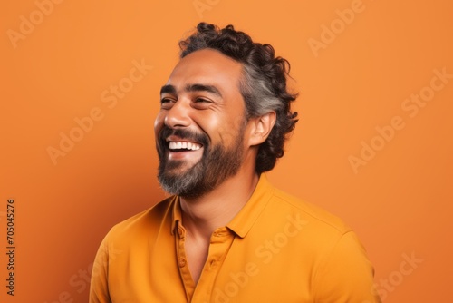 Portrait of a happy indian man laughing over orange background.