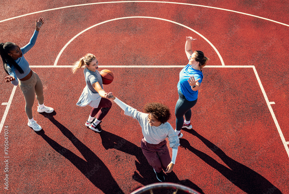 Diverse group of young woman having fun playing basketball outdoors.