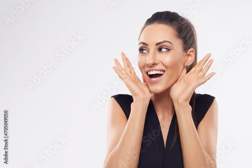 Shocked and surprised girl screaming covering mouth her hands.Beautiful Woman in black dress.Presenting your product.Expressive facial expressions emotions.