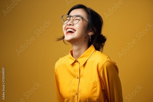 Portrait of a happy young asian woman in yellow shirt and glasses