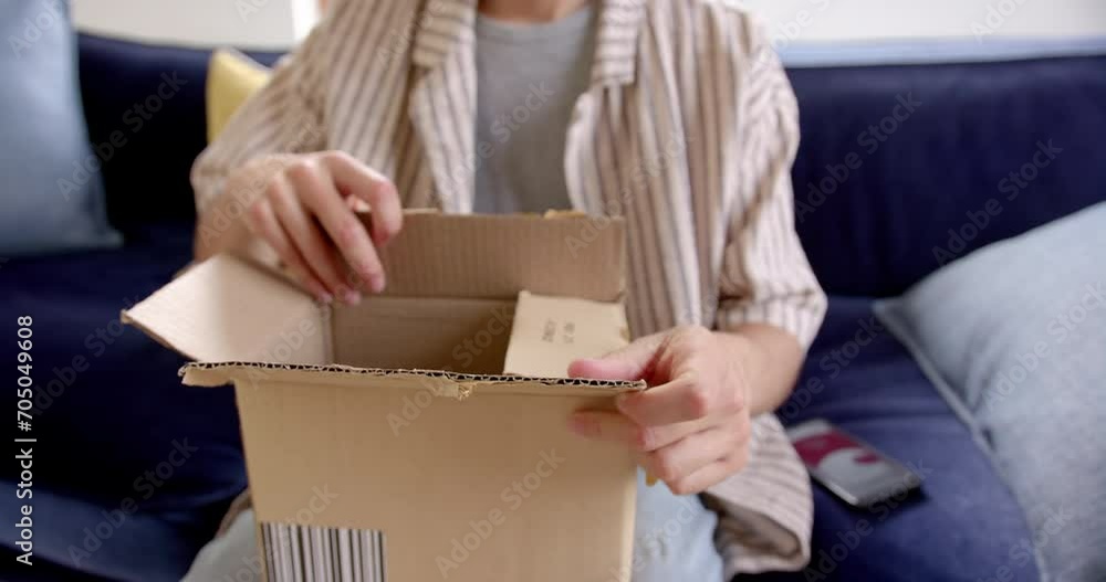 Midsection of excited biracial man opening delivery in cardboard box, slow motion Midsection of excited biracial man opening delivery in cardboard box, slow motion