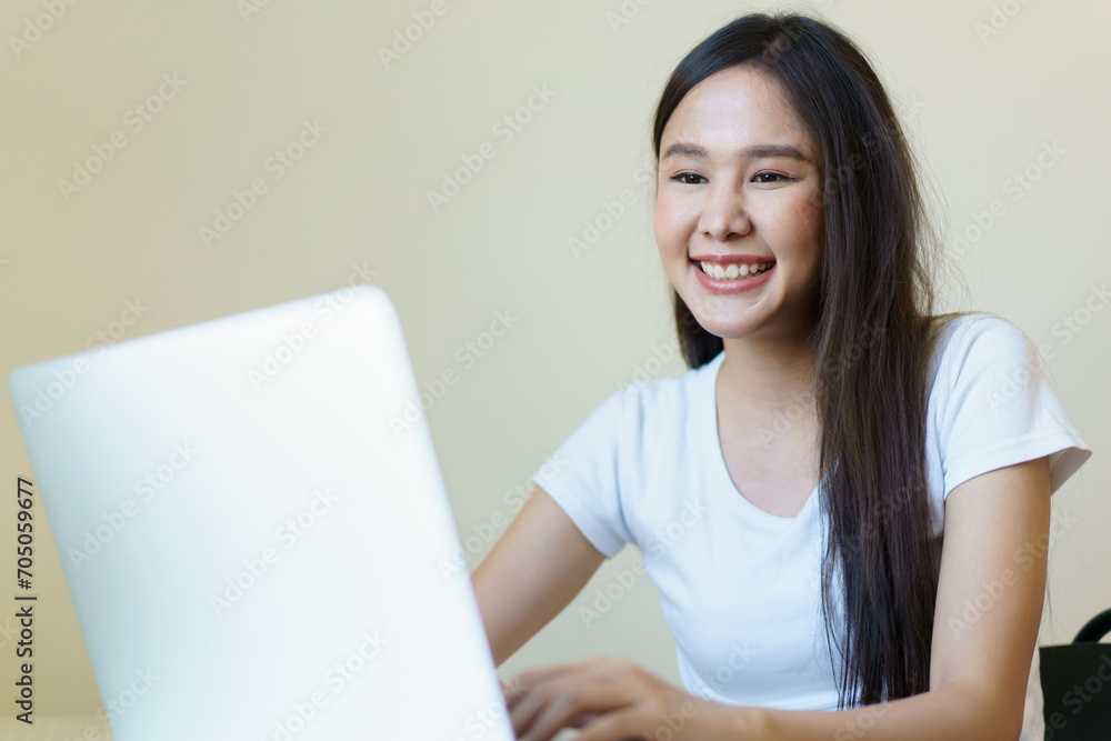 Asian beautiful woman checking e-mail and browsing the internet on laptop - notebook computer in morning. 
