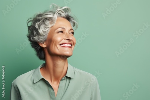 Portrait of a happy senior woman smiling against a green background.