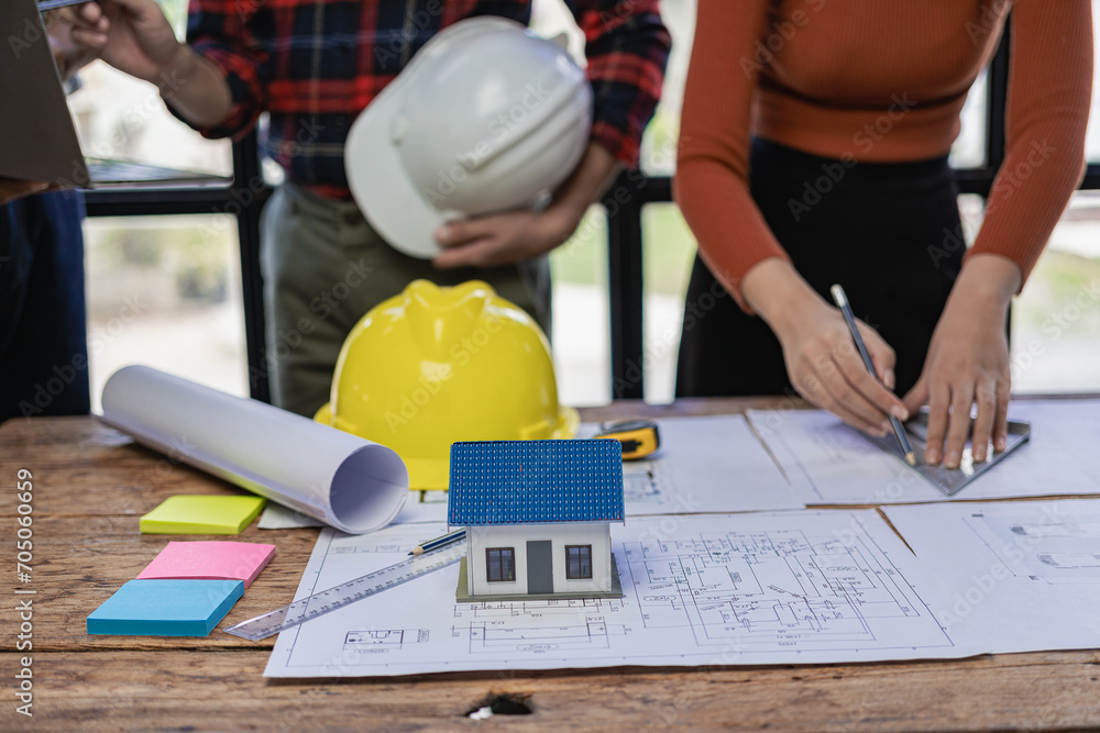 A team of construction workers and engineers meet to plan home construction and plan an office renovation project. The contractor talks to the architect and discusses the work in close proximity. A team of construction workers and engineers meet to plan home construction and plan an office renovation project. The contractor talks to the architect and discusses the work in close proximity.