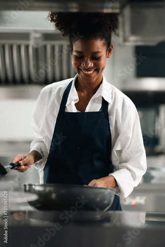 Happy African American woman standing with arms crossed while working as chef in a restaurant. Cooking class. culinary classroom. happy young african woman students cooking in cooking school. photo