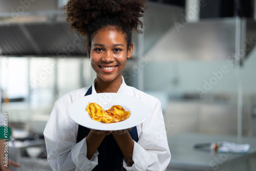 Portrait Happy African American female show omelet while working as chef in a restaurant. Cooking class. culinary classroom. happy young african woman students cooking in cooking school. photo