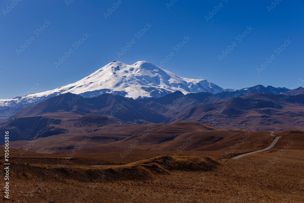Landscape of Mount Elbrus, snow-capped peak against blue sky background