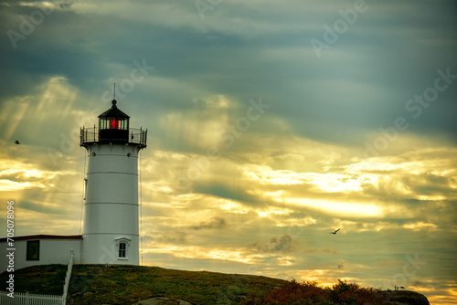 lighthouse Nubble against a dramatic sky background with sun rays and birds in the sky. USA. Maine. New England Seacoast.