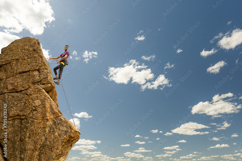 Person climbing in high mountains with yellow jacket rope and helmet in nature, confidence and risk, safety Person climbing in high mountains with yellow jacket rope and helmet in nature, confidence and risk, safety