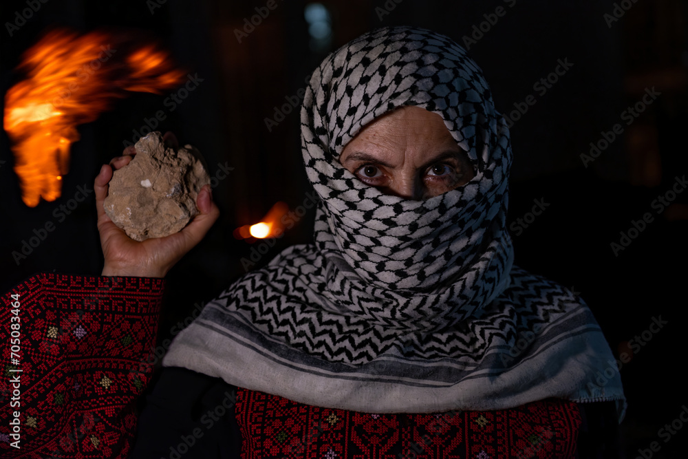 portrait for old woman holding stone which represents the only weapon against the occupation and will be the road to freedom