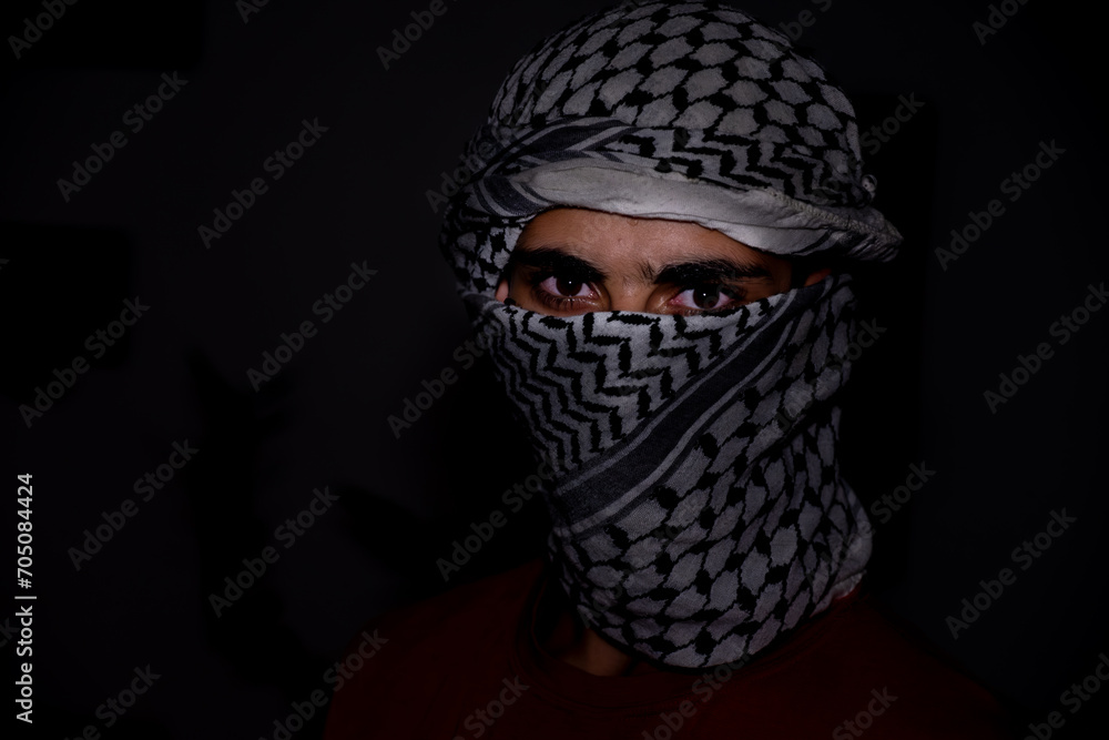 portrait of pearson wearing white keffiyeh on dark background with anger expression on his eyes 