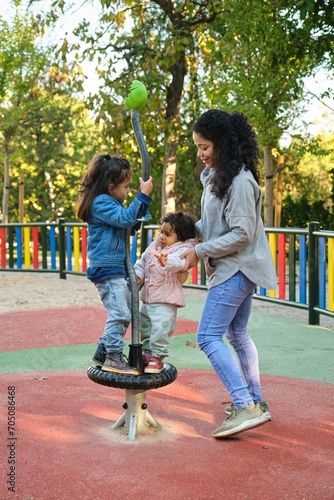 Canvastavla Happy Dominican mother playing with her children at the synchro spinner in a park