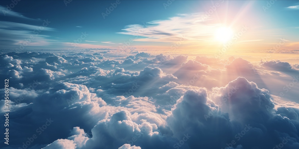 A breathtaking view above the clouds with sunlight piercing through. - obrazy, fototapety, plakaty 
