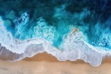Aerial view of ocean waves crashing onto a sandy shore.