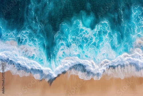 Aerial view of ocean waves crashing onto a sandy shore. © ParinApril