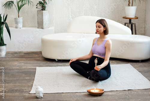 Calm pregnat female burning sage smudge stick and smelling smokein light room photo