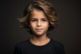 Portrait of a cute little boy with curly hairstyle on dark background