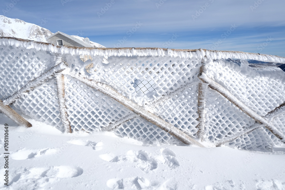 Snow-covered fence high in the mountains. Sunny bright day on Campo Imperatore, Gran Sasso Italy Snow-covered fence high in the mountains. Sunny bright day on Campo Imperatore, Gran Sasso Italy