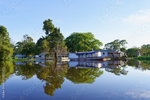 Wooden houses on stilts reflecting in the Amazon River, Amazonas state, Brazil photo
