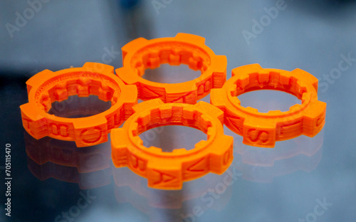Many orange detail printed on 3D printer close-up. Part 3D printed from molten plastic. FDM technologies. Additive progressive modern new technology. 3D printing technology. Innovation prototyping