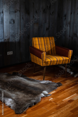 The sun shines on the reindeer skins on the floor and the armchair against the wall of boards photo