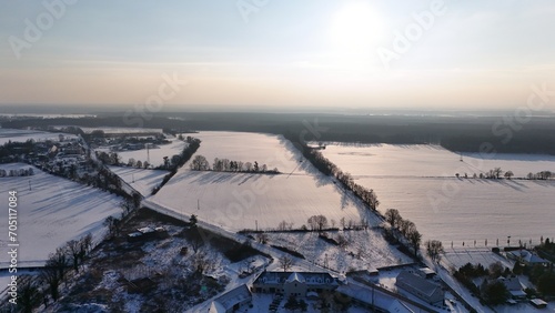 Widok miejscowości Dąbrowa przed zachodem słońca pola i zabudowania.