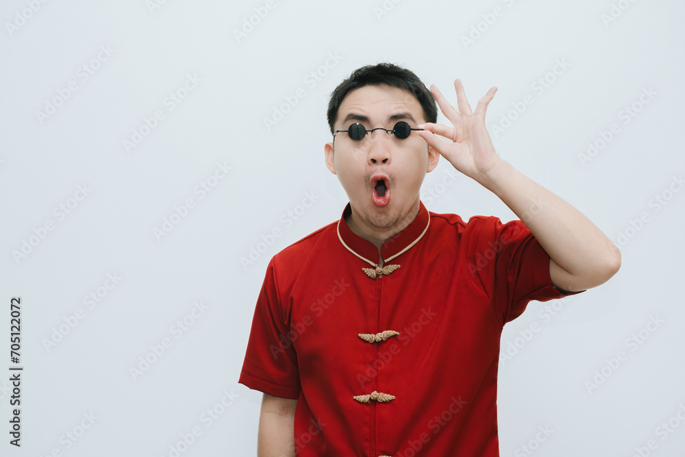 Wow face of Asian man wearing Cheongsam and black vintage sunglasses while looking at the camera on white background Wow face of Asian man wearing Cheongsam and black vintage sunglasses while looking at the camera on white background