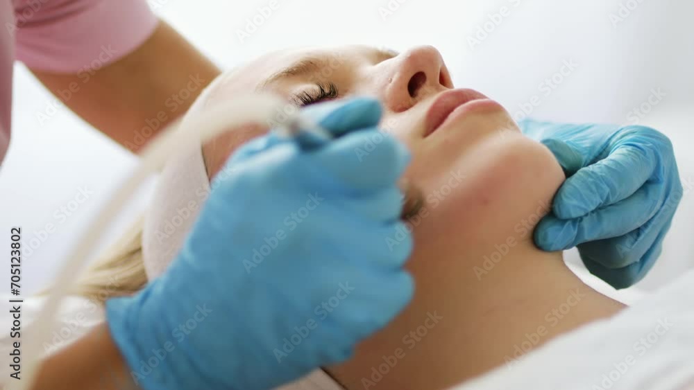 Beautician cosmetologist makes a procedure Microdermabrasion peeling of the face skin. Hardware cosmetology in clinic salon for client. Diamond face clean. Beautician cosmetologist makes a procedure Microdermabrasion peeling of the face skin. Hardware cosmetology in clinic salon for client. Diamond face clean.