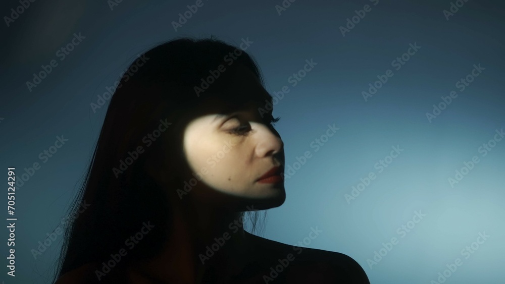 Portrait of attractive female model in the studio. Silhouette of woman isolated on dark light background, with round spotlight on face part. Portrait of attractive female model in the studio. Silhouette of woman isolated on dark light background, with round spotlight on face part.