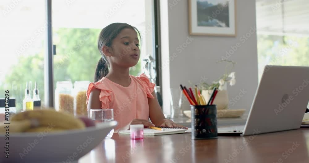 Happy biracial girl having elementary school class on laptop in kitchen raising hand, slow motion Happy biracial girl having elementary school class on laptop in kitchen raising hand, slow motion