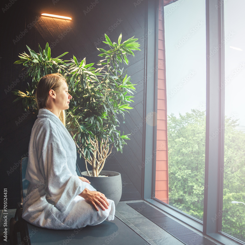Woman in white bathrobe lying on sofa and relaxing with orange cocktail at SPA.