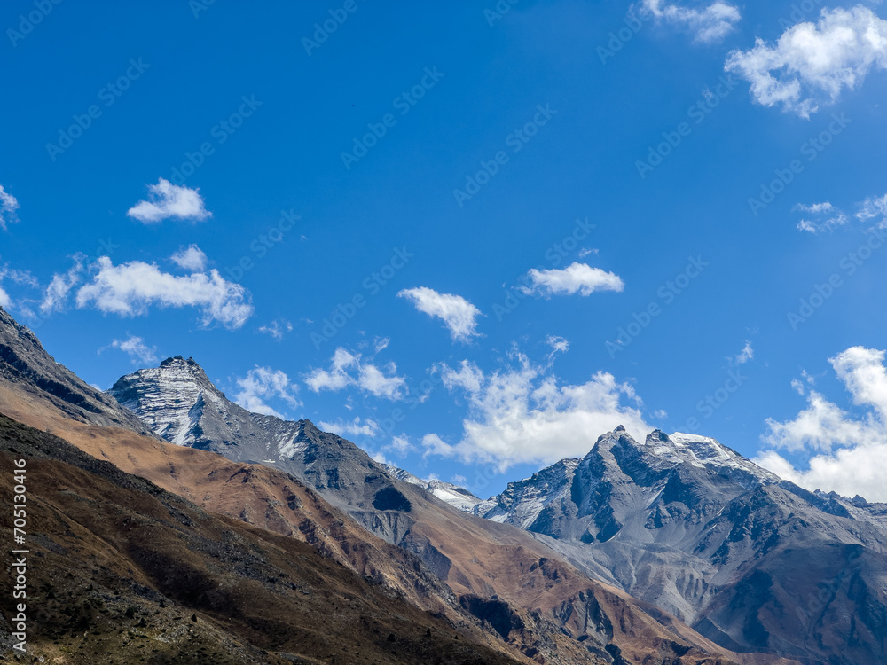 Cold climate landscape of the snow capped mountains with clouds and blue sky
