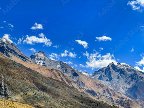 Cold climate landscape of the snow capped mountains with cloudy blue sky