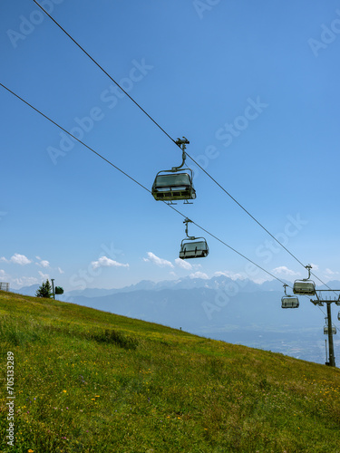 Sommerliche Seilbahn über grüner Bergwiese bei Villach in Kärnten
