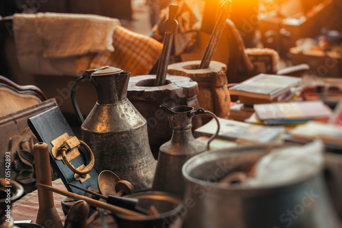 Vintage metal pitcher, vintage mortars, old door knob , old books on the countertop in sunday flea market. Details from antique bazaar. photo