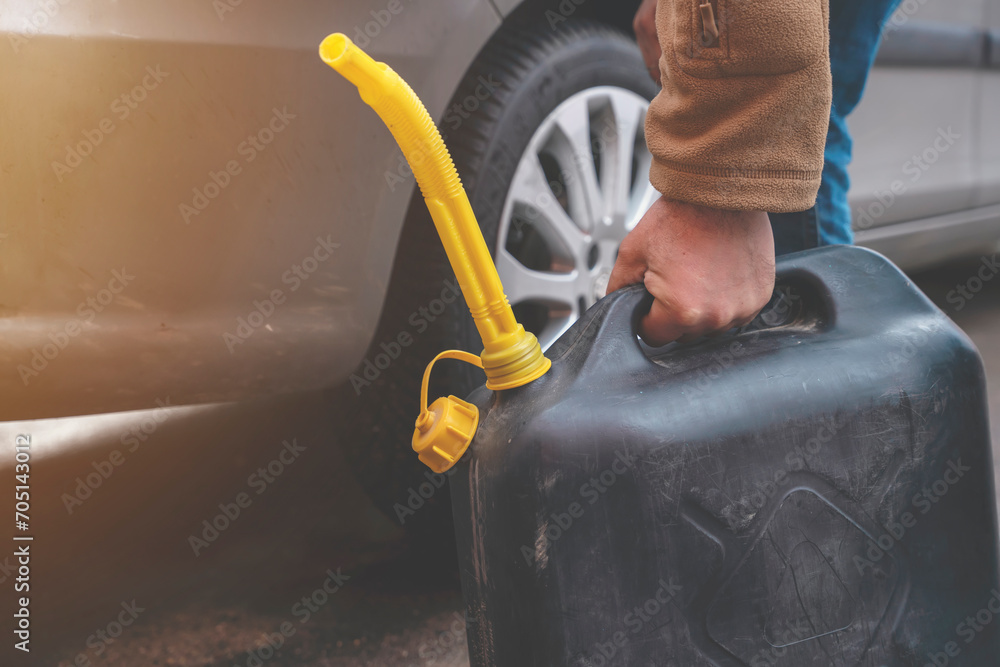 A man filling fuel tank of his car with diesel fuel from the jerry can as there is no fuel at the petrol station, close up - obrazy, fototapety, plakaty 