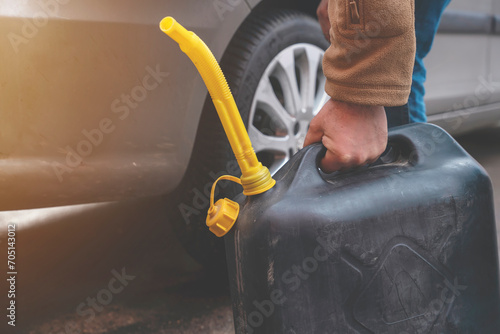 A man filling fuel tank of his car with diesel fuel from the jerry can as there is no fuel at the petrol station, close up photo