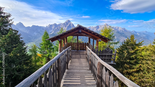 Wooden viewing platform connected by bridge with vistas to majestic mountain ranges of untamed Sexten Dolomites, South Tyrol, Italy. Lookout from mount Helm (Monte Elmo), Carnic Alps, Austria border