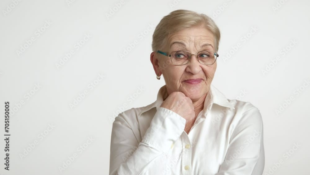 Medium shot of senior intelligent lady holding fist near chin, shrugging shoulders, expressing dissatisfaction, curling lips, showing contempt, sneer. High quality 4k footage Medium shot of senior intelligent lady holding fist near chin, shrugging shoulders, expressing dissatisfaction, curling lips, showing contempt, sneer. High quality 4k footage