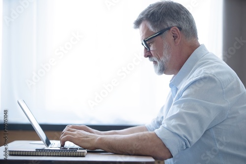 Mature businessman working from home using laptop © opolja