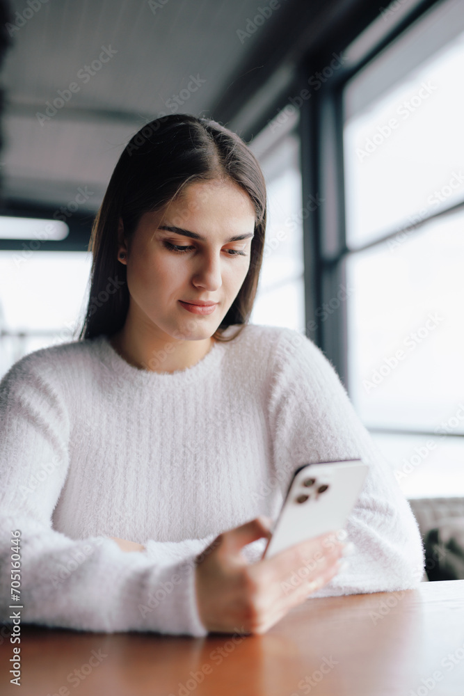 Woman in white clothes using smartphone sitting in cafe Woman in white clothes using smartphone sitting in cafe