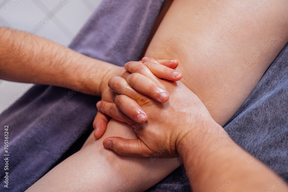 Fototapeta premium Close up of female foot getting gentle massage. Masseuse holds woman leg in her hands. Young client lies and enjoys relaxing procedure in beauty salon. Spa treatment. Yourself and skincare. Copy spase