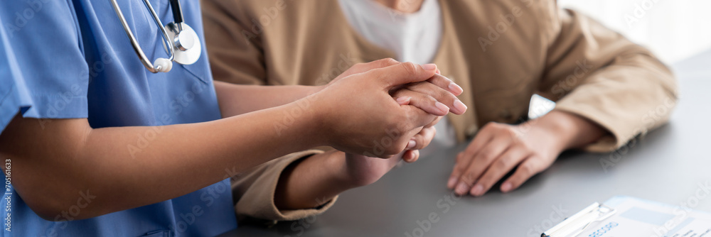 Doctor or nurse providing compassionate healthcare consultation while holding young patient hand for being supportive and professional as medical staff in doctor clinic or hospital office. Neoteric