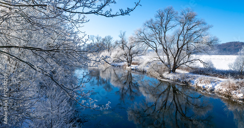 Winter panorama in Sauerland at Ruhr river near Arnsberg and Wickede. Frosted trees and fields on a very cold morning with blue sky and bright snow. Seasons greetings atmosphere in idyllic landscape. photo