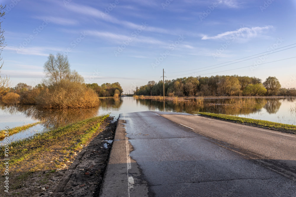 Natural disaster, spring flood. A road in a rural area is flooded with water. Spring river flood. Natural disaster, spring flood. A road in a rural area is flooded with water. Spring river flood.