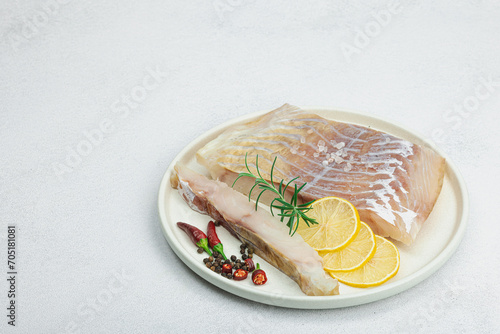 Raw pollock (Pollachius virens) fillet. Fresh fish for healthy food lifestyle. Spices and herbs photo