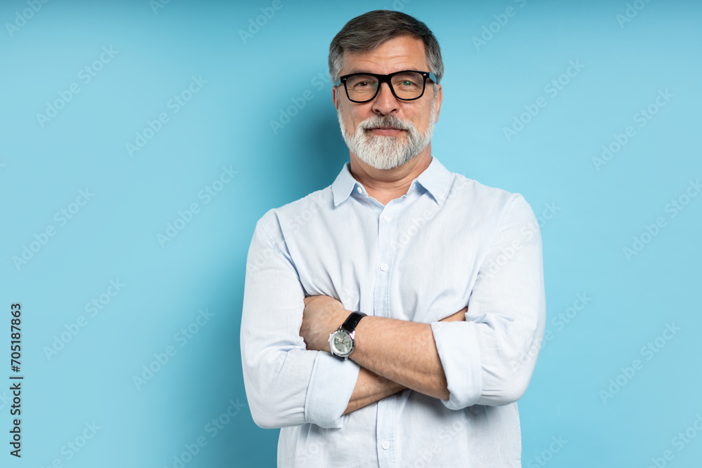 Bearded middle-aged man wearing glasses posing over blue studio background Bearded middle-aged man wearing glasses posing over blue studio background